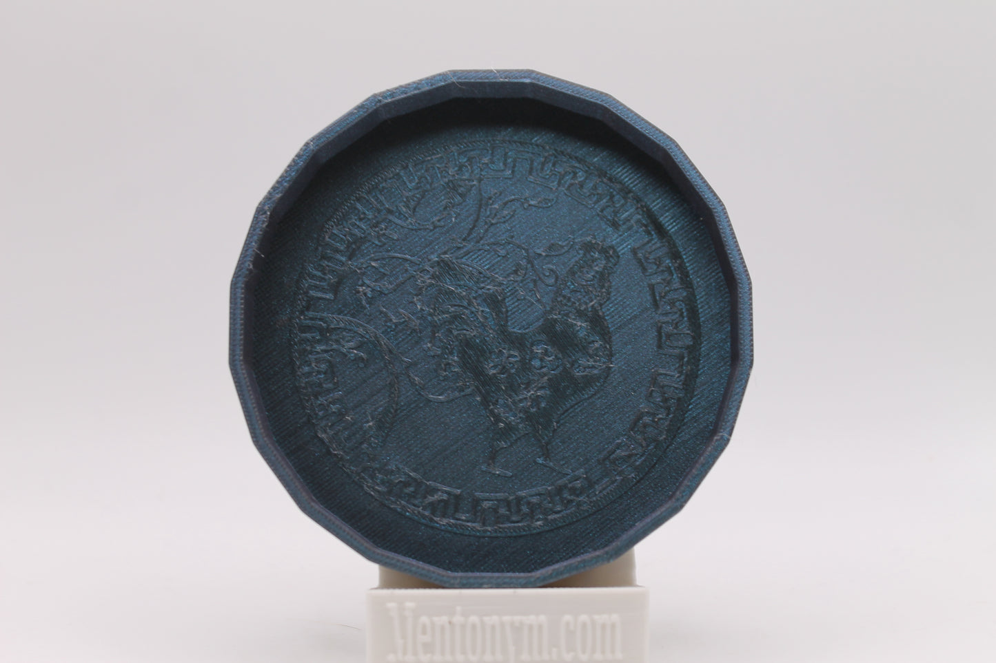 Dark blue decorative object with engraved design on a white background